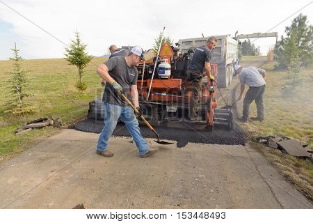 Colbert, WA - October 24, 2016: Workers from Black Diamond Asphalt Paving, LLC., repairing patches and re-paving a private road/driveway