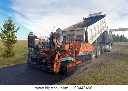 Colbert, WA - October 24, 2016: Workers from Black Diamond Asphalt Paving, LLC., repairing patches and re-paving a private road/driveway