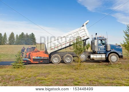 Colbert, WA - October 24, 2016: Workers from Black Diamond Asphalt Paving, LLC., repairing patches and re-paving a private road/driveway