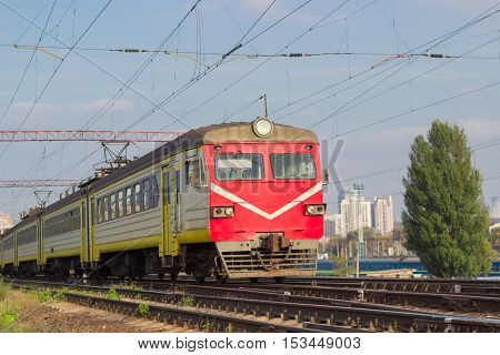 Several carriages of moving urban electric multiple unit on the background of urban development