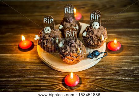 Halloween cupcakes with tombstone cake topper and candle on an old wooden table