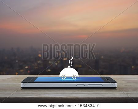 Restaurant cloche flat icon on modern smart phone screen on wooden table over blur of cityscape on warm light sundown Food delivery concept