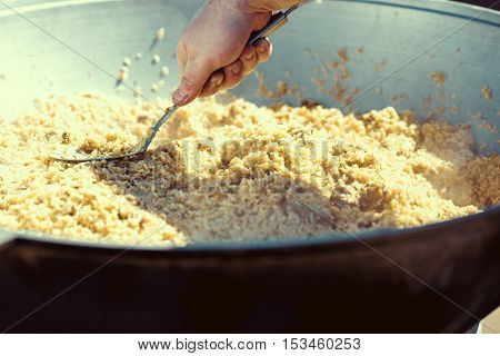 A delicious pilaf with pork carrots and rice with spicy spices and onions in a cauldron with a wooden spatula.