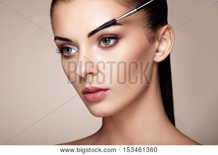 Beautiful brunette woman paints the eyebrows. Beautiful woman face. Makeup detail. Beauty girl with perfect skin