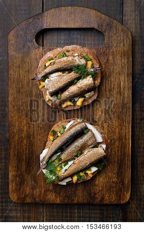 Sandwich with sprats egg and green onion on wooden cutting board top view
