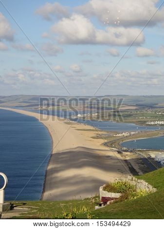 View from Portland over the village of Chesil along Chesil Beach with clouds creating shadows on beach