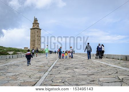 La Coruna Spain - May 28 2016: People walking on promenade towards Hercules tower Torre de Hercules roman lighthouse UNESCO world heritage Coruna Galicia Spain.