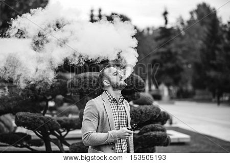 Men with beard vaping electronic cigarette outdoor