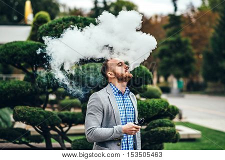 Men With Beard Smoking Electronic Cigarette Outdoor