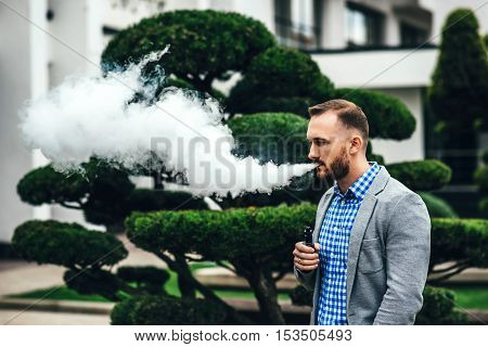 Men With Beard Smoking Electronic Cigarette Outdoor