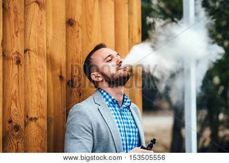 Men With Beard Smoking Electronic Cigarette Outdoor