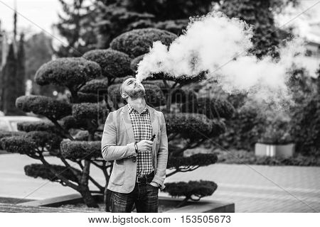 Men With Beard Smoking Electronic Cigarette Outdoor