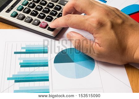 Business man press on calculator with financial chart and graph