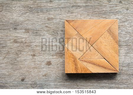 Tangram puzzle in square shape on wooden table