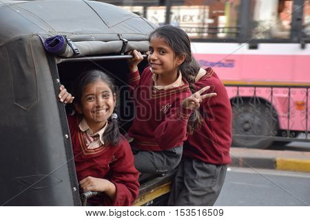 JAIPUR, RAJASTHAN, INDIA - FEBRUARY 05, 2016 - Three unidentified indian kids smiling in front of the camera inside a small truck before going to school