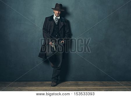 Mysterious Mature Retro 1900 Western Man Standing Against Gray Wall.