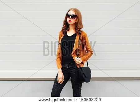 Fashion Pretty Woman Wearing A Sunglasses Brown Jacket Black Handbag Over Grey Background