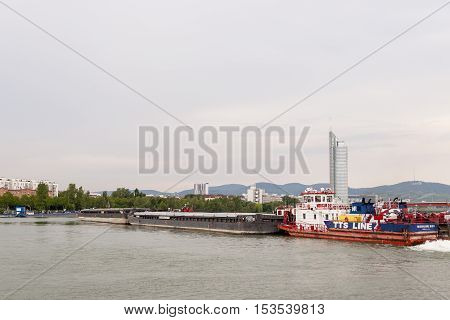 Vienna / Austria - July 21st 2014: Picture of Mercur 201 romanian cargo boat pushing two barges on the Danube river in front of the Millenium Tower