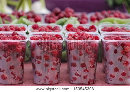 Fresh raspberries in plastic boxes at farmers market.