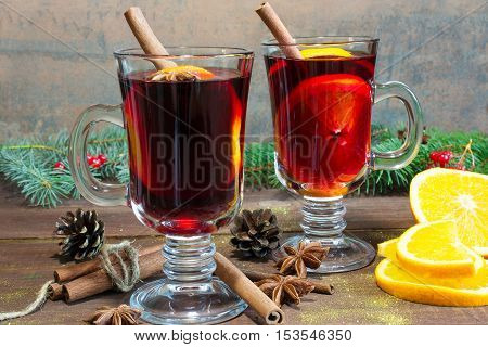 hot christmas mulled wine with cinnamon sticks anise and orange on wooden table background with fir branches and pine cones