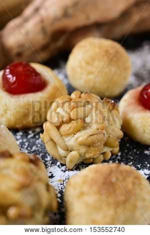 closeup of some homemade panellets, typical confection eaten in All Saints Day in Catalonia, Spain, on a rustic kitchen table with some sweet potatoes in the background