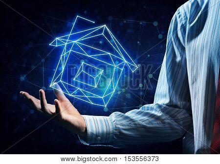 Close of buinessman holding in palm glowing house symbol