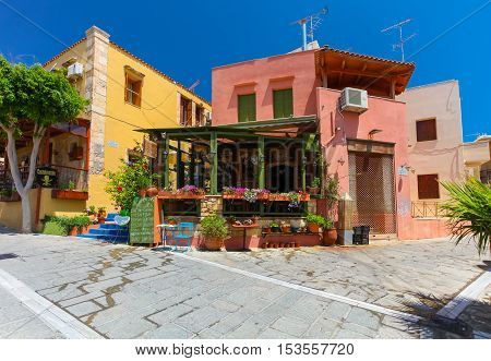 Rethymnon, Island Crete, Greece - July 1 2016: Cozy Cretan small cafe with flowers outside with ad on the green board about Cretan cuisine