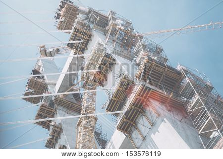 Multiple scaffolding construction crane on a modern rope bridge under construction in Rio de Janeiro on a bright summer day