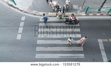 Top view of people are moving across the pedestrian crosswalk in the city street (Aerial photo)