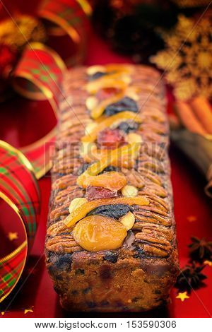 Traditional Christmas fruit cake with festive decorations and Xmas spices on red background.Vertical compositon