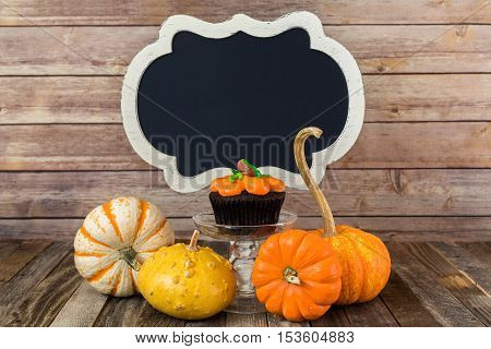 Fall pumpkin muffin with blank chalkboard sign and decorative gourds