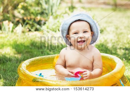 Beautiful Baby Girl In Cotton Panama Cap Bathes In Yellow Inflatable Swimming Paddling Pool