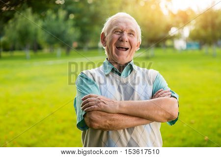 Senior man is laughing. Male with crossed arms outdoor. What a witty joke. You raised my mood.