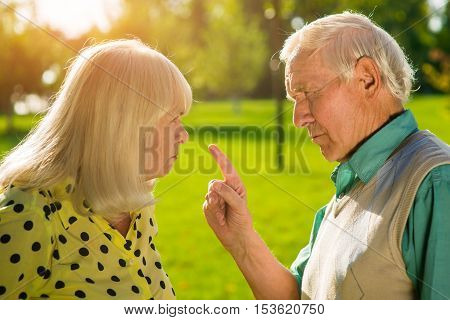 Man points finger at woman. Old grumpy couple. Difficulties in relationships. You don't understand me.