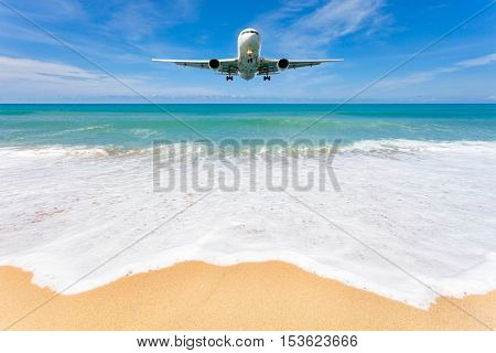 Airplane landing above beautiful beach and sea background