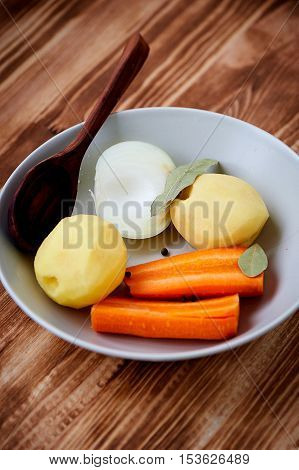 Poseshenie vegetables to prepare vegetable soup with spices on a light plate . wooden background