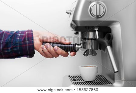 Professional espresso machine pouring strong looking fresh coffee into a neat ceramic cup