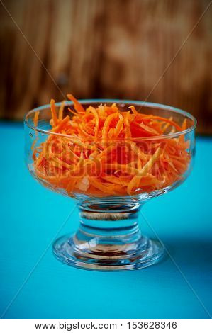 Grated carrot in a glass Cremant, on a blue background