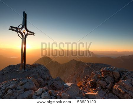 Cross Raised  At Mountain Summit  In Alps. Sharp Peak, Daybreak Sun