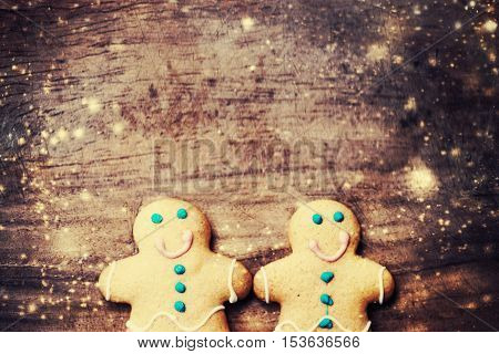 Christmas homemade gingerbread cookies over wooden table. Christmas Card with decorations and falling snow