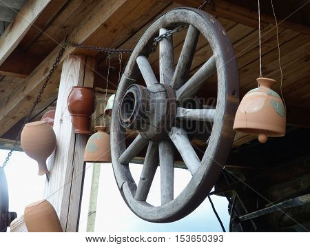 Obsolete old wheel of the horse cart. Hanging under the roof of a rural hut. Retro. Close-up. Ural, Russia.
