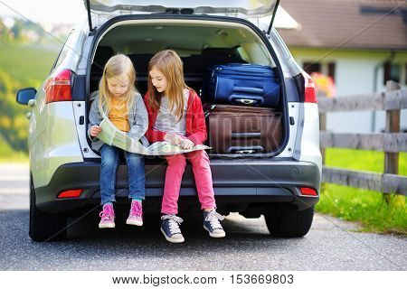 Two Adorable Little Sisters Exploring A Map Before Going On Vacations With Their Parents