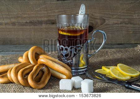 Tea in the Cup holder with bagelssuger and lemon on old wooden table.