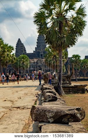 Ancient ruins of temple complex Angkor Wat surrounded by palm trees Siem Reap Cambodia. Selective focus on the rock in the foreground