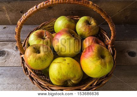 ripe autumn apples in the basket, on wooden background.