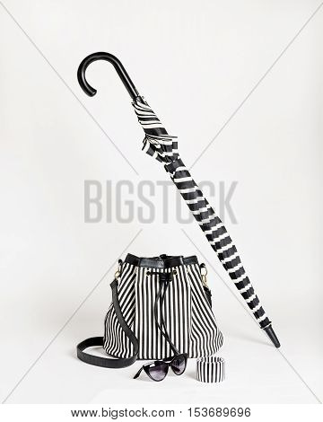 Fashion accessories - black-and-white striped bag umbrella bracelet and glasses. Selective focus.