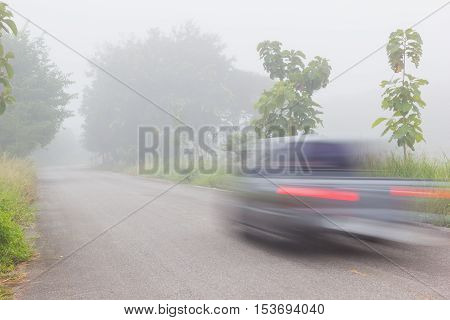 Motion blur of car on road on foggy morning along green tree lined road in the morning Thailand.