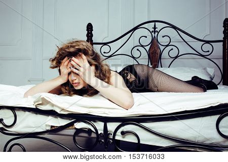 crying woman laying in bed, winter depression holding head with hands, having hangover close up