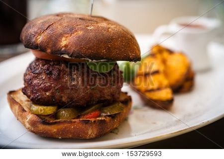 Beefburger with fried sweet potatoes served on a white plate