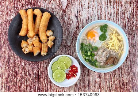 Rice porridge with mined pork and chicken lever served with side dish as Patongko (deep-fried dough stick) and spicy sour fillin.